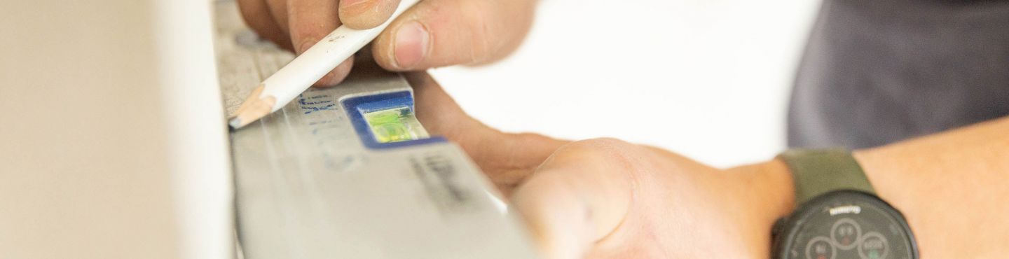 Eine Person zeichnet eine gerade Linie an die Wand mit einer Wasserwaage