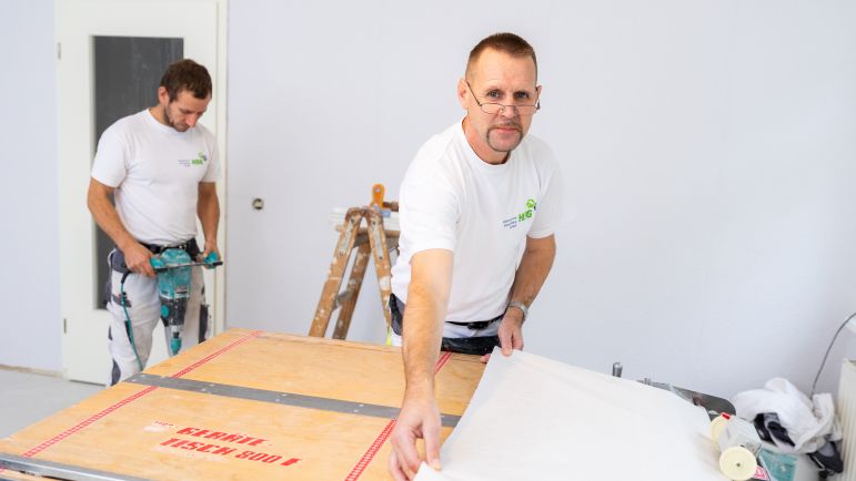 Zwei Mitarbeiter der HSG tapezieren