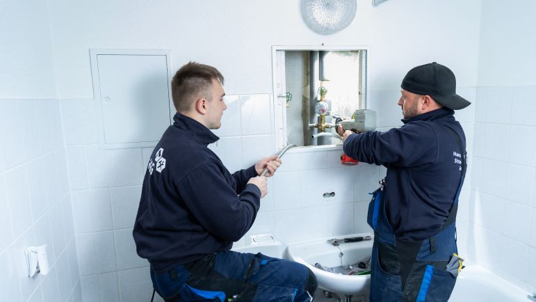 Zwei Mitarbeiter der HSG reparieren einen Wasseranschluss