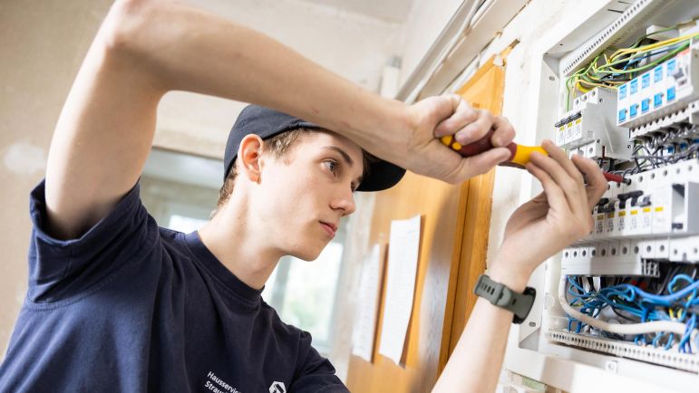 Ein Mitarbeiter der HSG schraubt im Stromkasten
